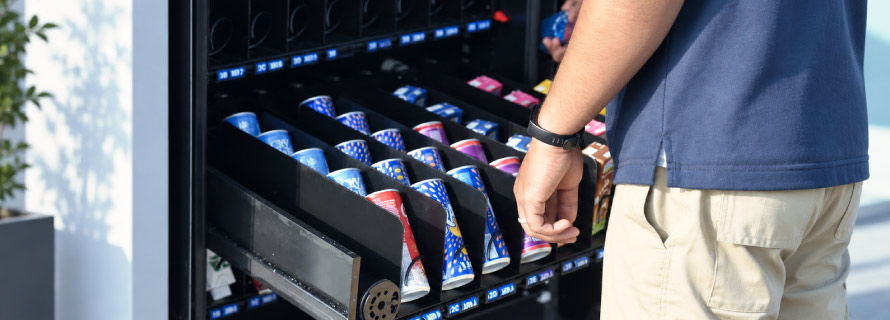 Υπάλληλος ανεφοδιάζει αυτόματο πωλητή με snacks και προϊόντα.